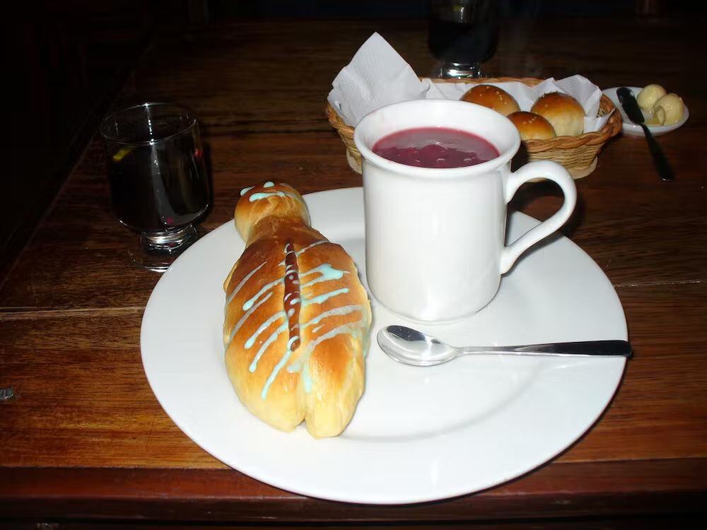 Colada Morada (derecha) servida junto una guagua de pan (izquierda). Juan Jorge Arellano / Wikimedia Commons, CC BY-SA