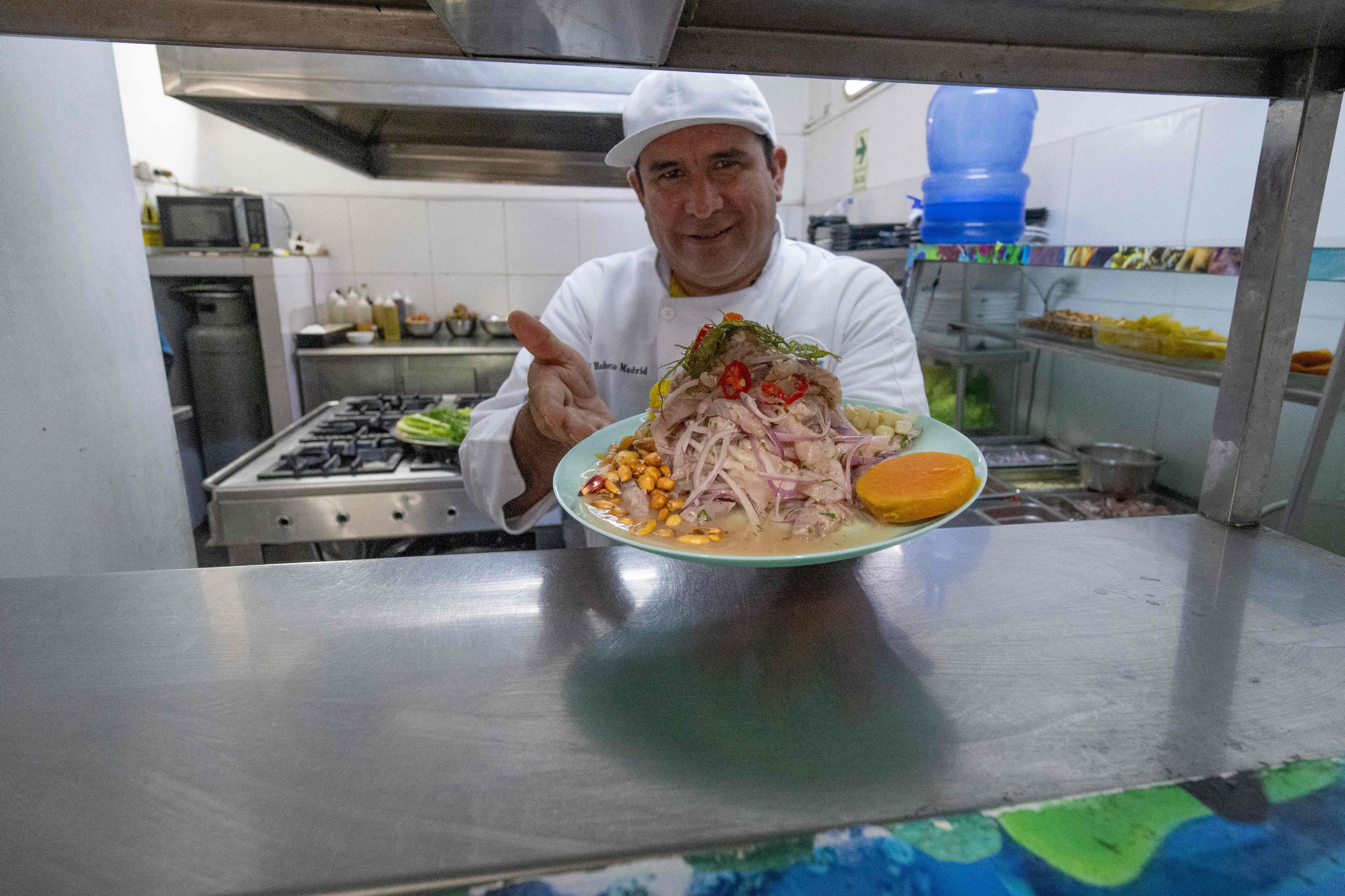 El chef peruano Roberto Madrid muestra un plato de cebiche tradicional en su restaurante Aroma de Mar, en Lima. Foto: Cris BOURONCLE / AFP