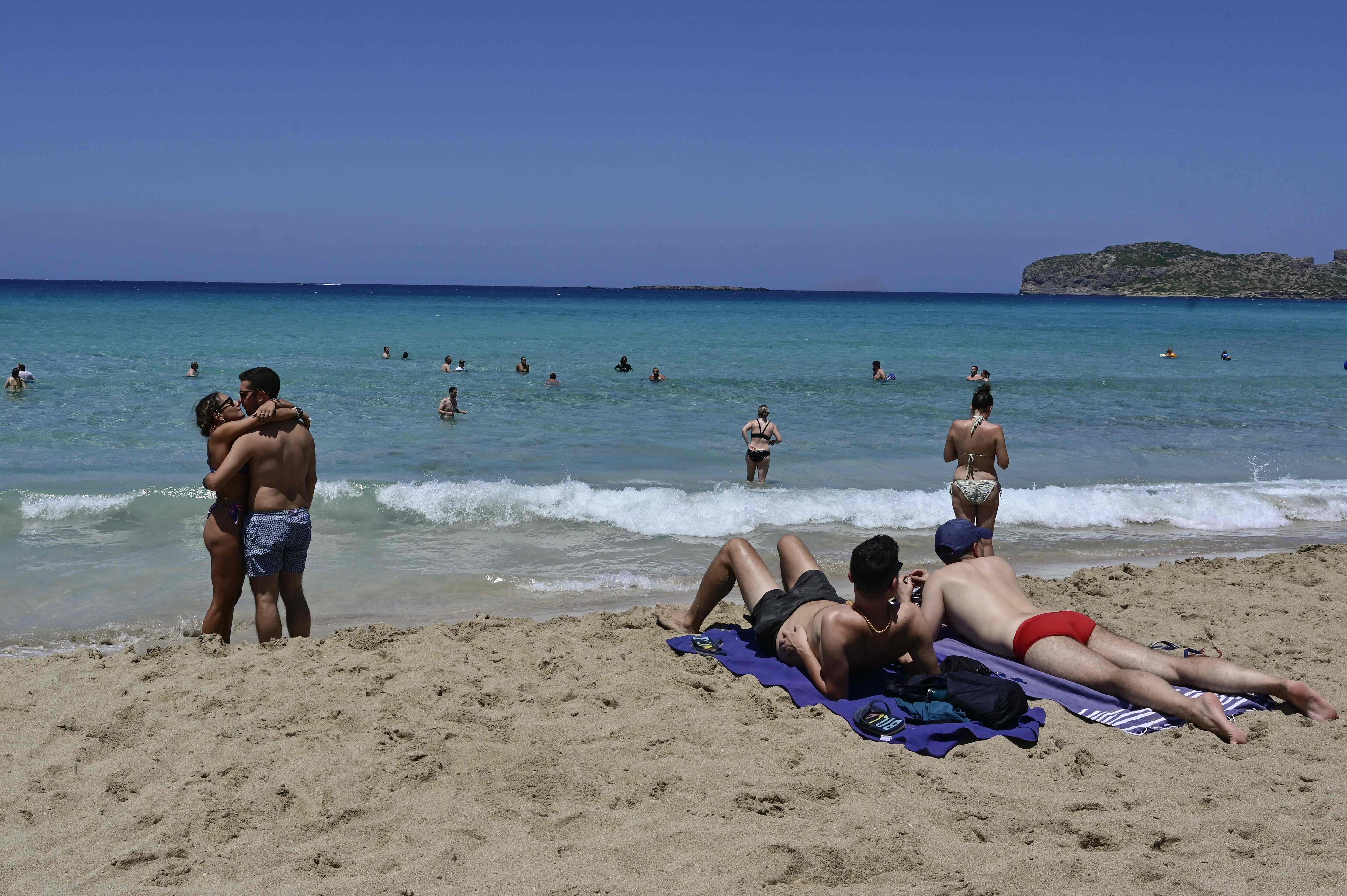 Turistas disfrutan de la playa en Phalasarna, al noroeste de la isla mediterránea griega de Creta el 20 de julio de 2022, mientras que las temperaturas se mantienen en niveles normales en ese país para la temporada a pesar de la ola de calor en el norte de Europa.