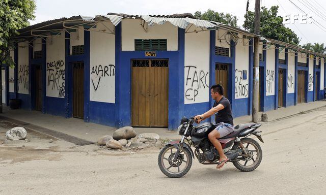 Fotografía de archivo del 19 de febrero de 2022 de una persona mientras pasa en moto frente a varios grafitis de las FARC, en Puerto Nariño.