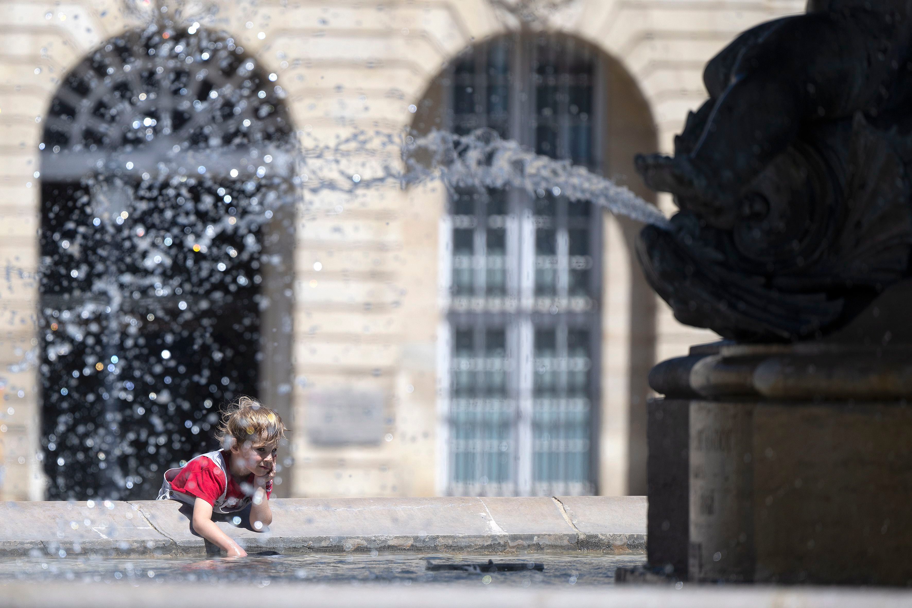 Un niño se rocía con agua de la fuente en la Place de la Bourse, durante la ola de calor, en la ciudad francesa de Burdeos. EFE/ Caroline Blumberg 
