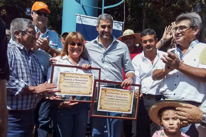 Sara López, directora general del Senasa, y el presidente paraguayo, Mario Abdo Benítez, reciben un reconocimiento de la comunidad Ñupy San Rafael, tras inaugurar un nuevo pozo de agua. SENASA