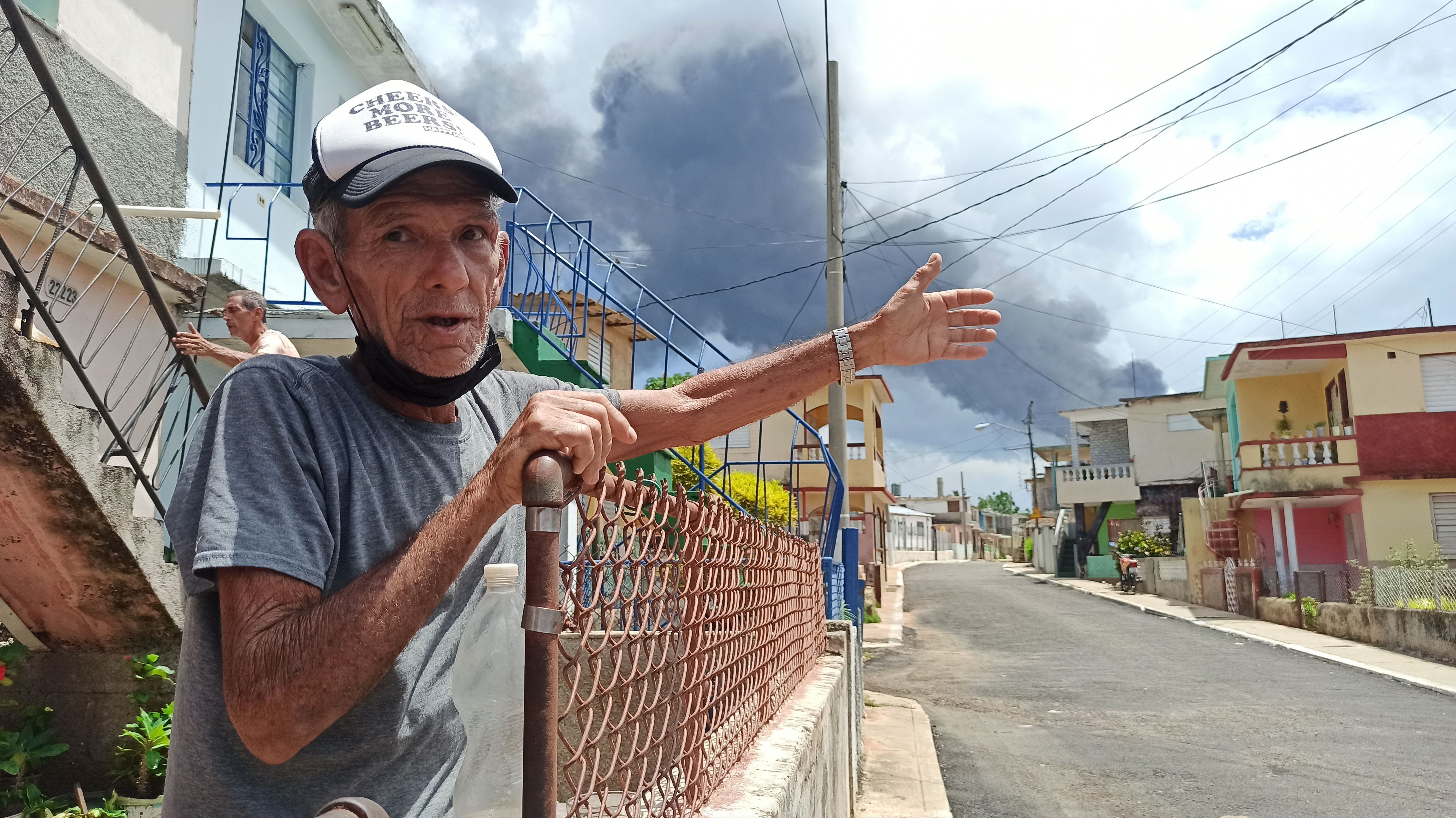 Oriol González señala hacia la zona donde se presenta un incendio en un depósito de combustible hoy, en el barrio vecino a la zona del incendio, en Matanzas (Cuba). EFE/Ernesto Mastrascusa 