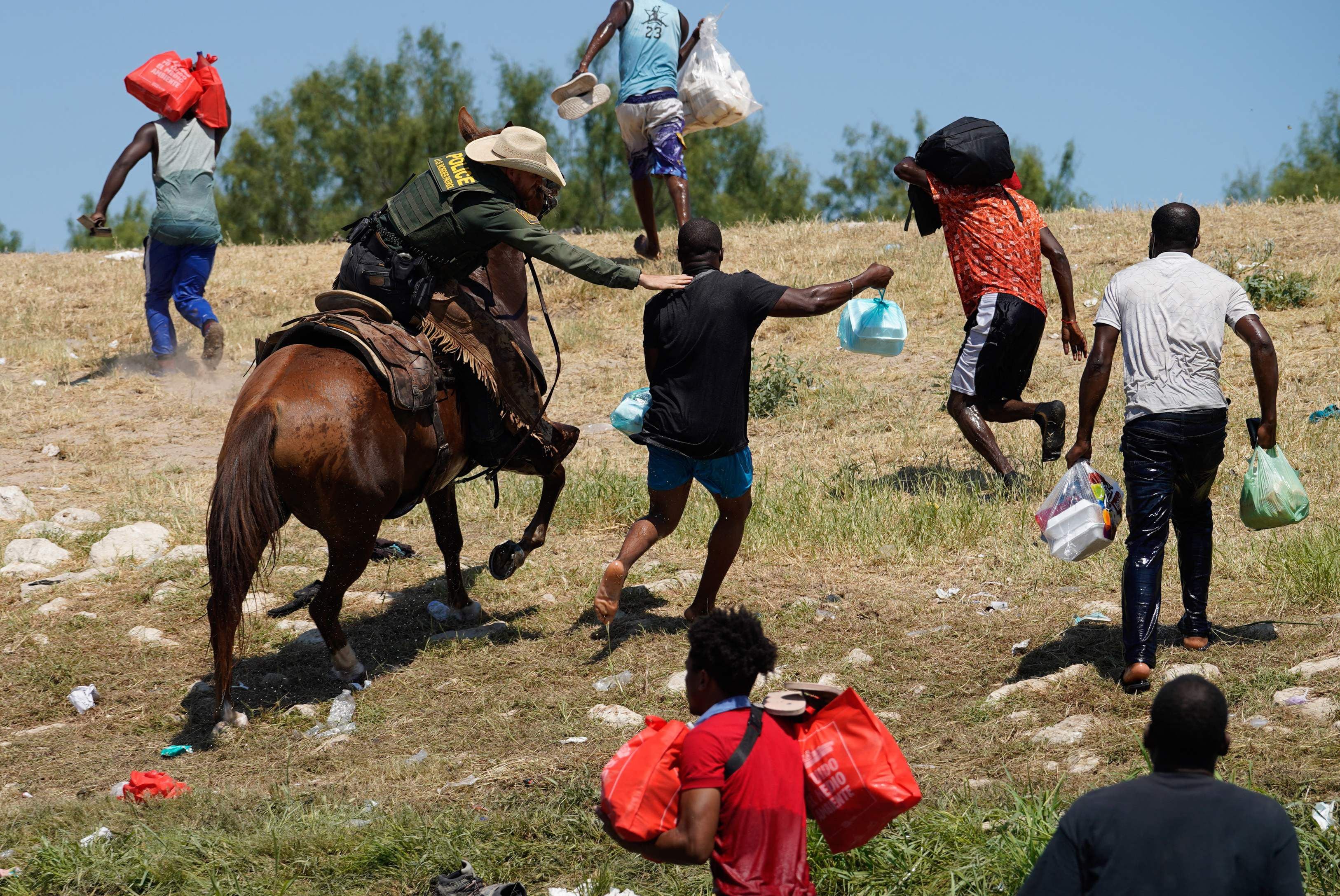 Un agente de la Patrulla Fronteriza de los Estados Unidos a caballo intenta evitar que un migrante haitiano ingrese a un campamento en las orillas del Río Grande cerca del Puente Internacional Acuña del Río en Del Río, Texas, el 19 de septiembre de 2021. (Foto de PAUL RATJE / AFP)