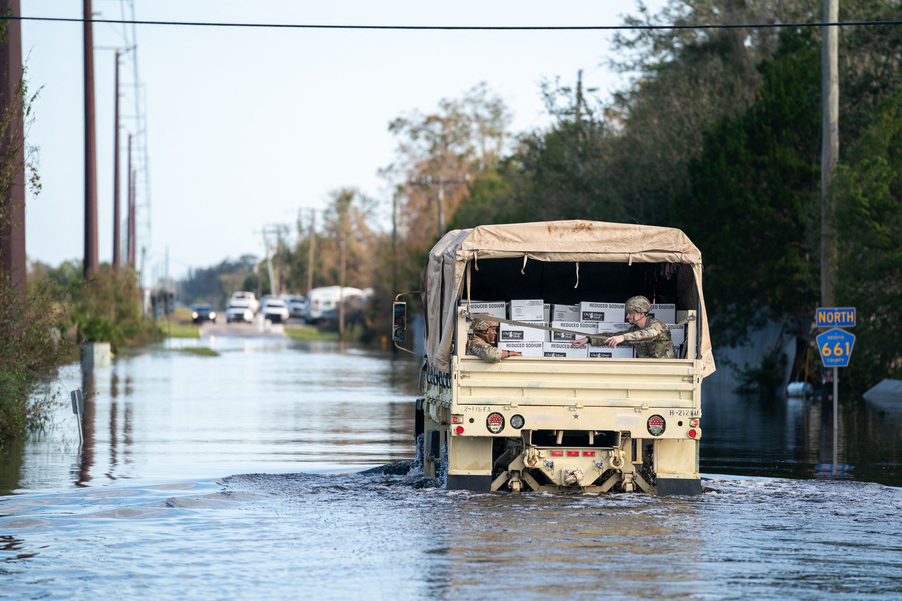 Los miembros de la Guardia Nacional transportan comidas listas para comer a una comunidad aislada por las inundaciones tras el huracán Ian cerca del río Peace el 4 de octubre de 2022 en Arcadia, Florida.
