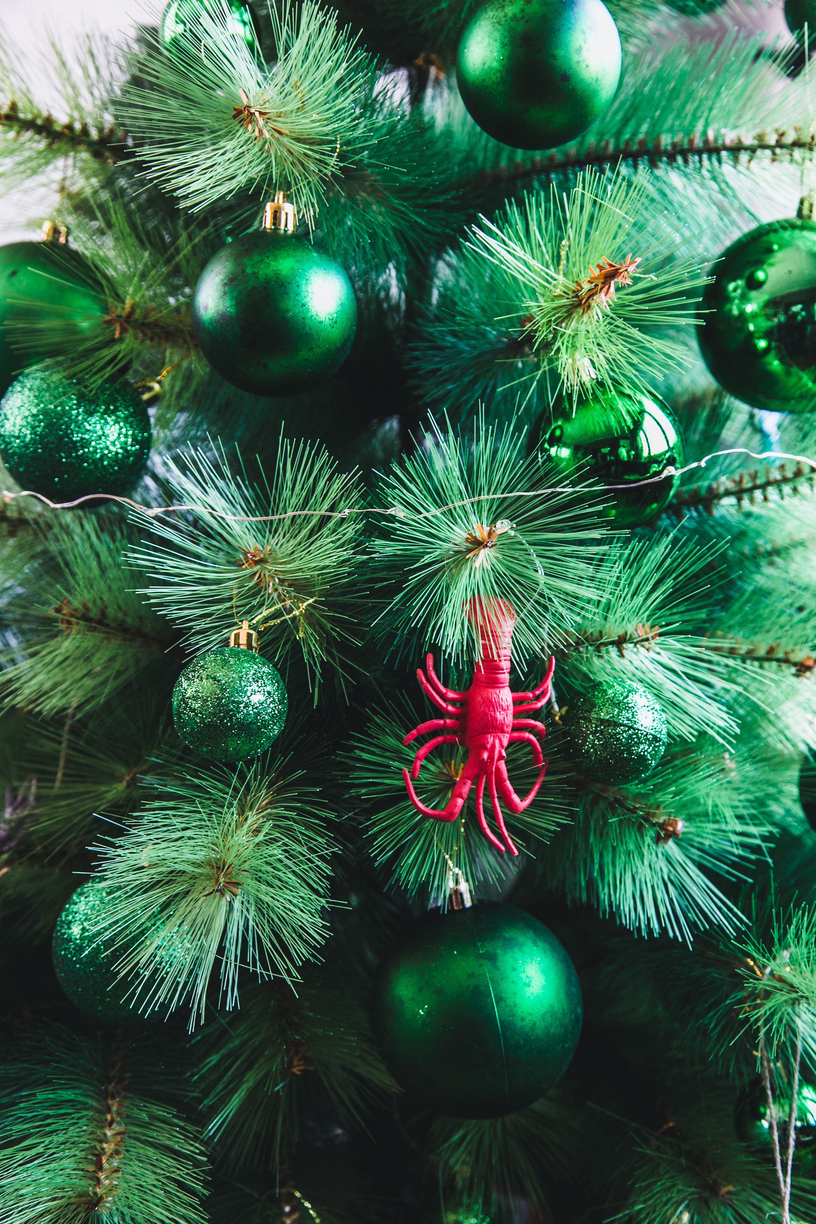 Árbol de Navidad con adornos verdes y un detalle en rojo.