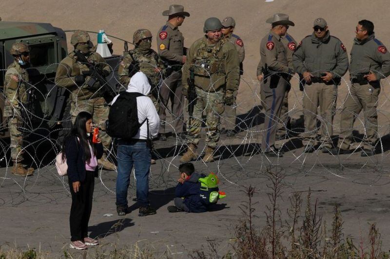 Migrantes piden la Guardia Nacional de Texas dejarles que se entreguen a la Patrulla Fronteriza en El Paso, Texas. GETTY IMAGES