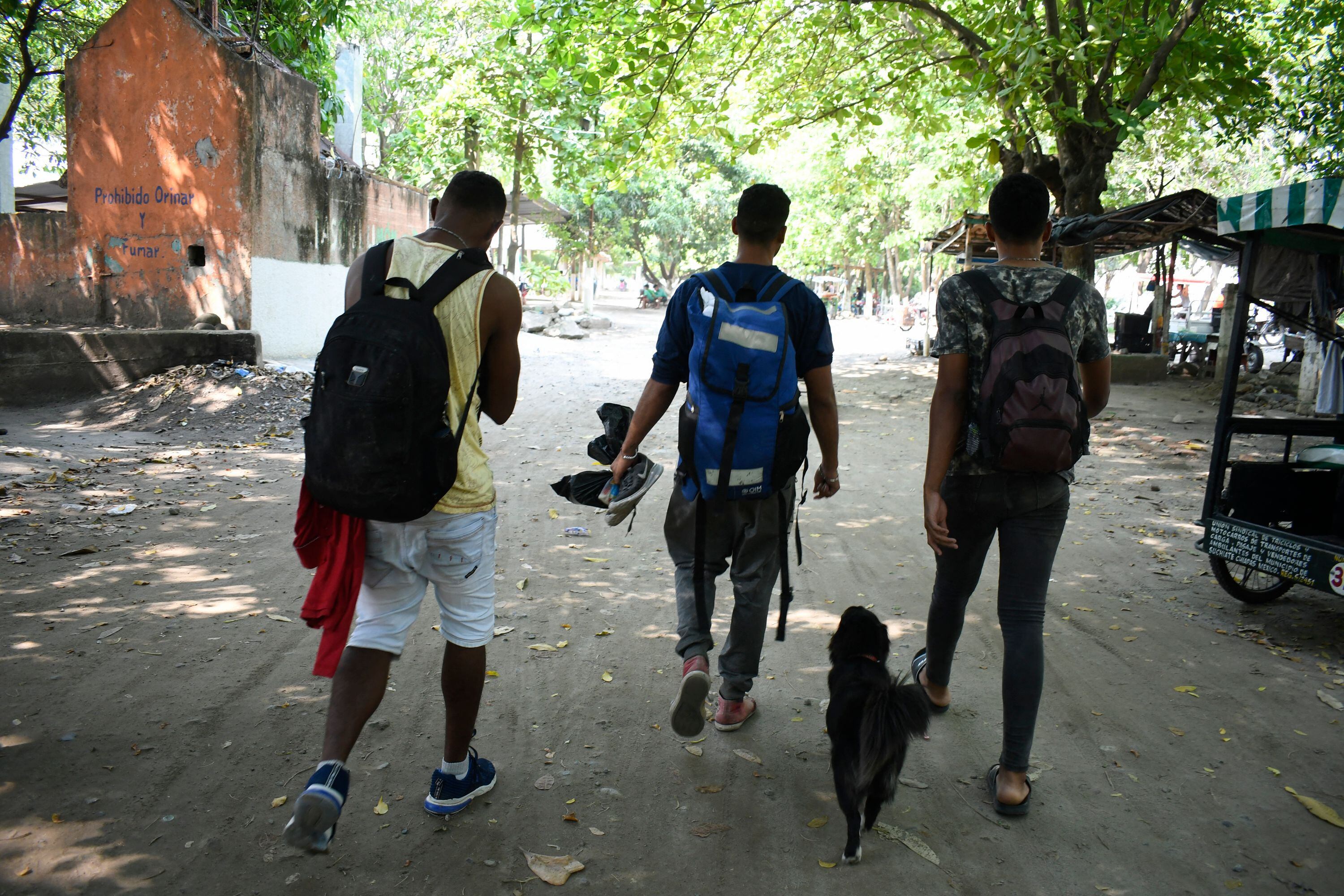 El migrante venezolano Gilberto Rodríguez y su perro Negro caminan con sus compañeros migrantes Darwin Montiel y Sergio Muñoz después de cruzar en una balsa improvisada el río Suchiate en Ciudad Hidalgo, estado de Chiapas, México.
