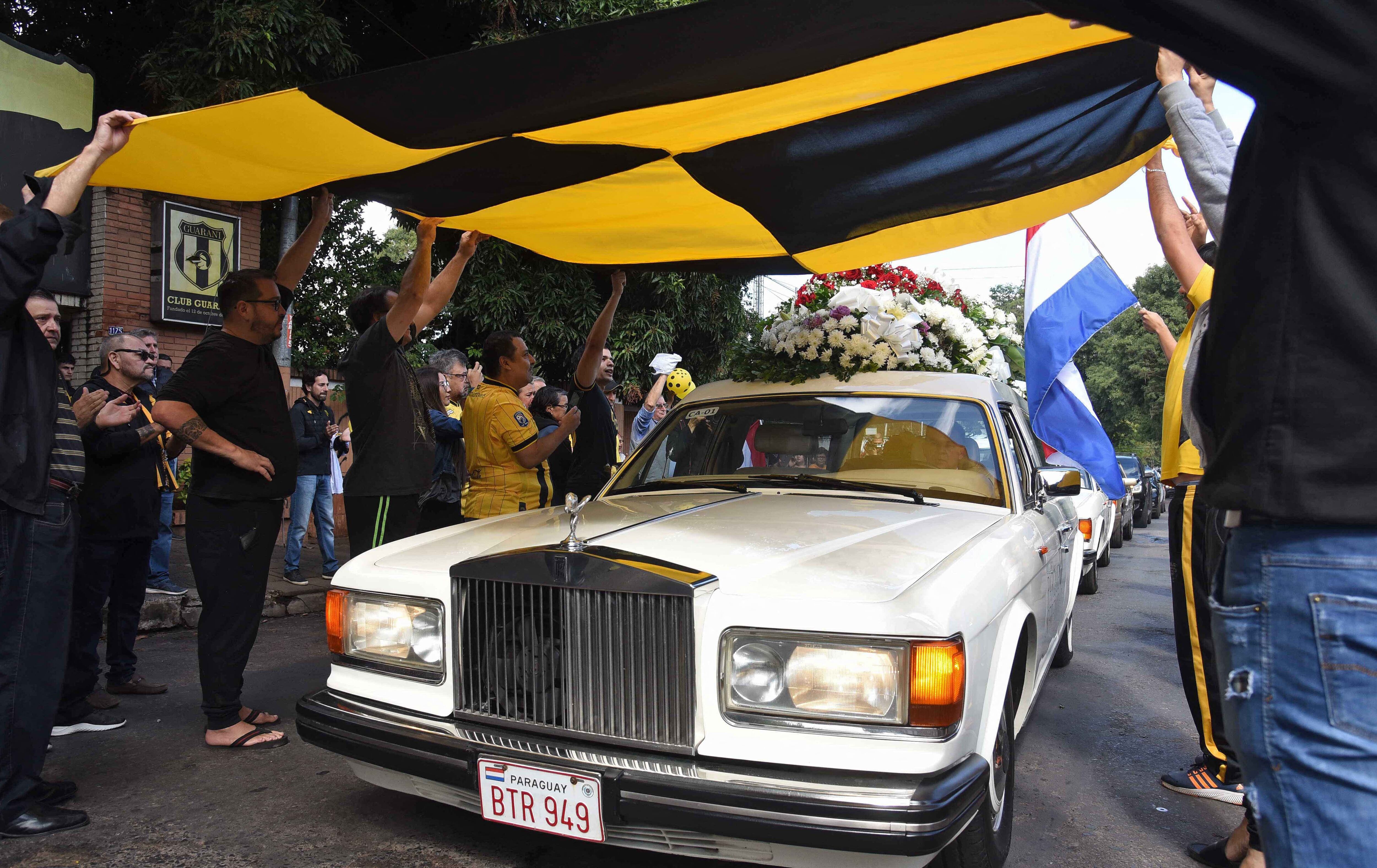 Aficionados del equipo de fútbol paraguayo Guaraní rinden homenaje al fiscal antidrogas Marcelo Pecci, quien también era hincha y miembro de la junta directiva, al pasar el coche fúnebre con su féretro antes de su funeral. (Foto por Daniel DUARTE / AFP)