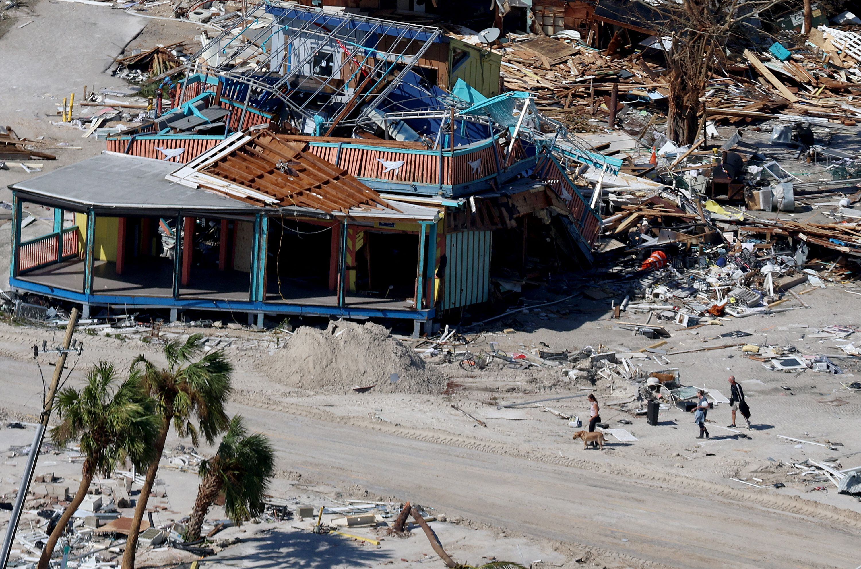 La gente pasa frente a un edificio destruido cuando el huracán Ian pasó por el área el 29 de septiembre de 2022 en Fort Myers Beach, Florida.