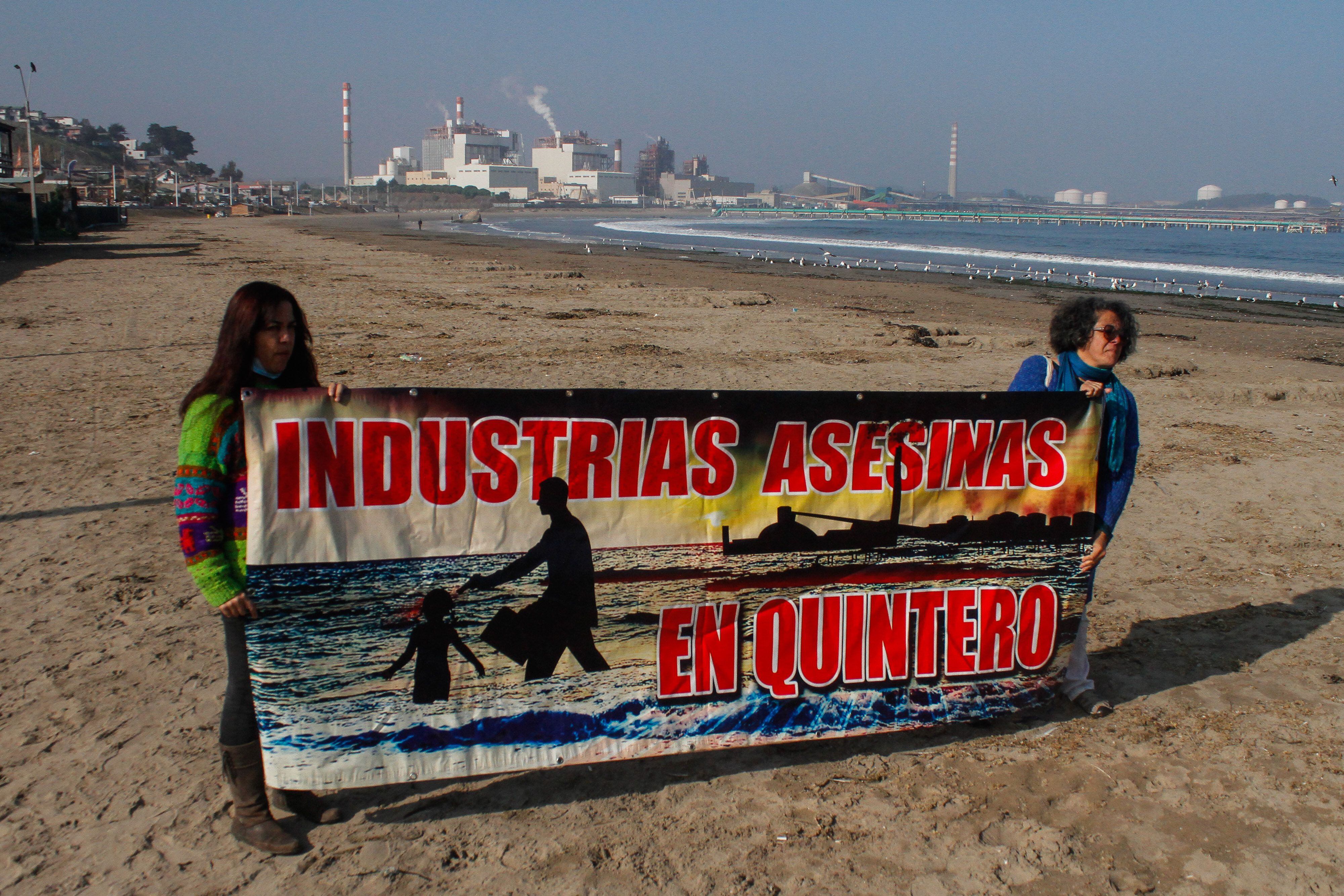 Dos personas sostienen un cartel durante una manifestación en distintos lugares de la Bahía de Quineros-Puchuncaví para exigir medidas contra la industria después un caso de contaminación en Valparaiso (Chile). EFE/ Cristobal Basaure 