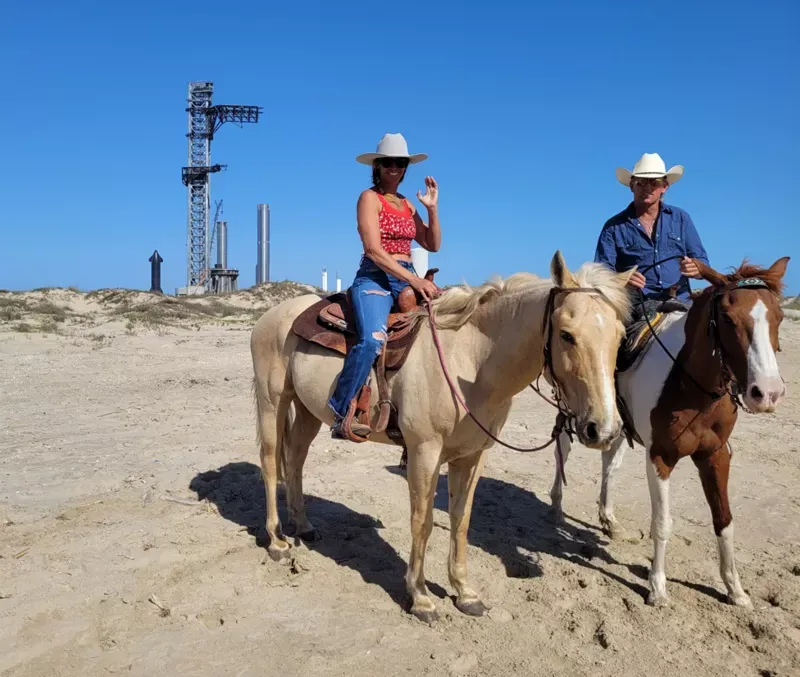 Gene Gore con su pareja y los caballos en Boca Chica Beach, con la plataforma de lanzamiento de SpaceX detrás. Analía Llorente