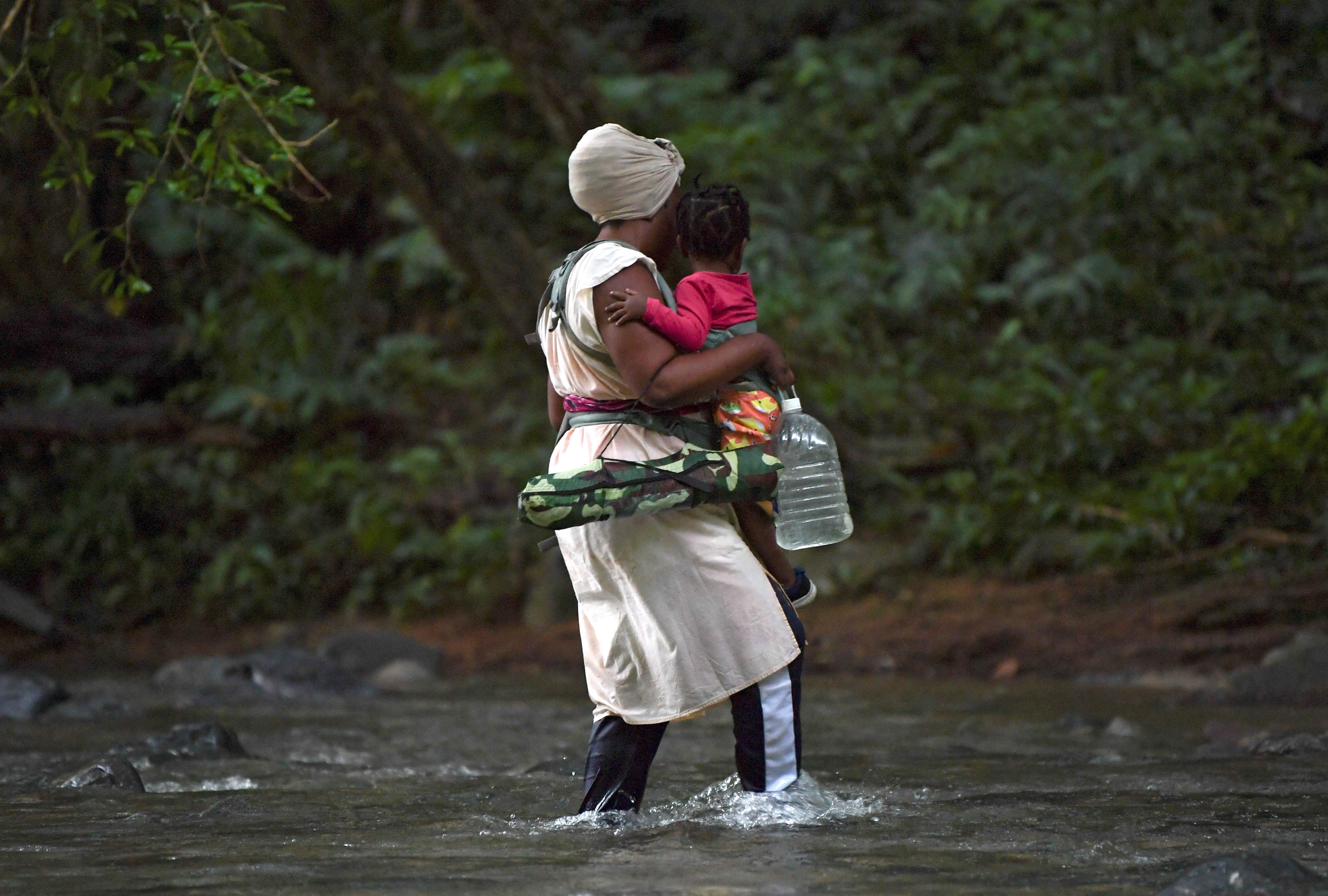 En esta foto de archivo tomada el 26 de septiembre de 2021, una mujer migrante haitiana carga a un niño mientras cruzan la selva del Tapón del Darién, cerca de Acandi, departamento de Chocó, Colombia, en dirección a Panamá, en su camino tratando de llegar a los EE. UU. (Foto de Raúl ARBOLEDA / AFP)