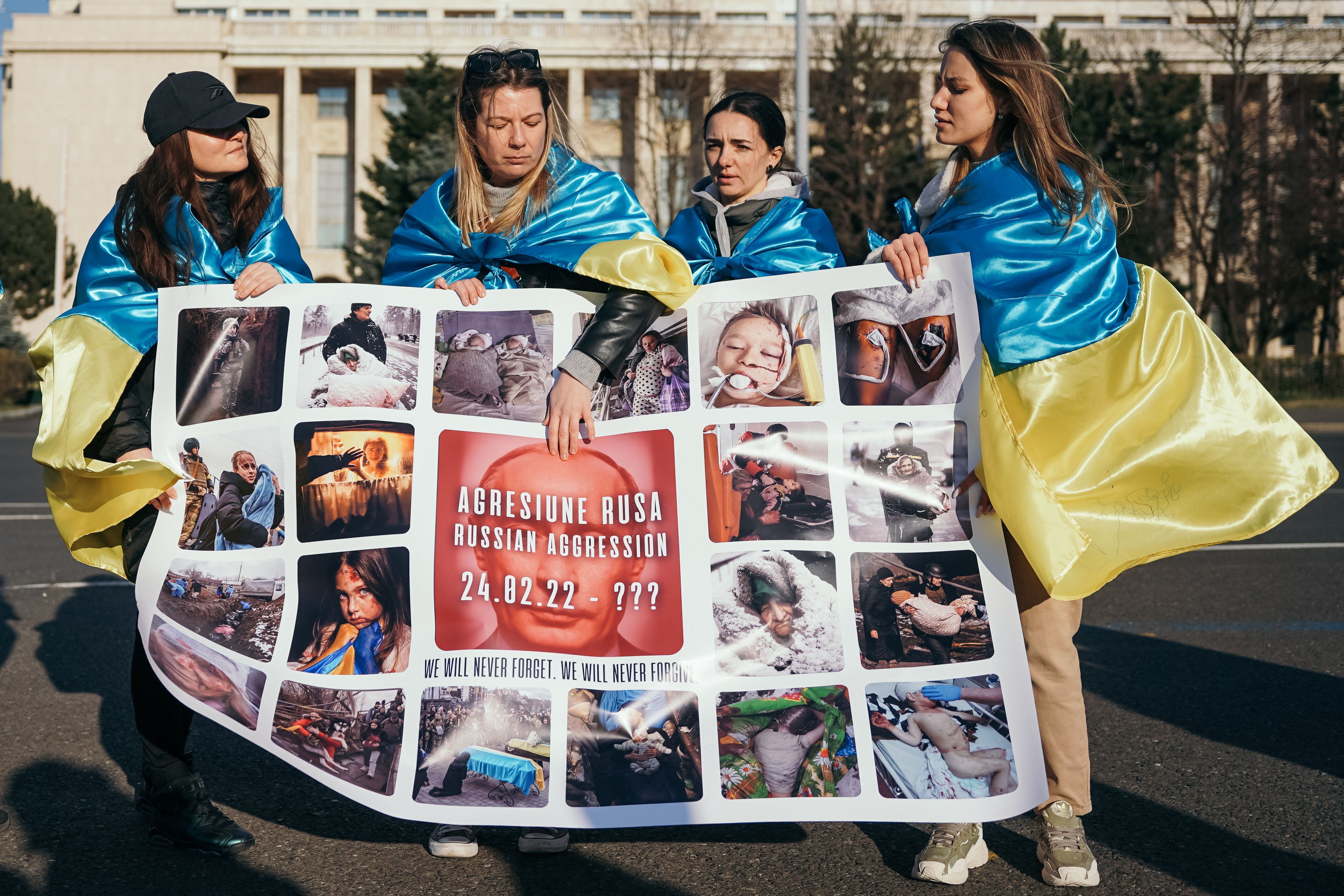 Mujeres ucranianas exhiben una pancarta con las letras que dicen "Agresión rusa - 24 de febrero - ¿hasta" y una imagen del presidente ruso, Vladimir Putin, durante una manifestación de solidaridad con Ucrania en Bucarest el 19 de marzo de 2022. Foto de Andrei PUNGOVSCHI / AFP